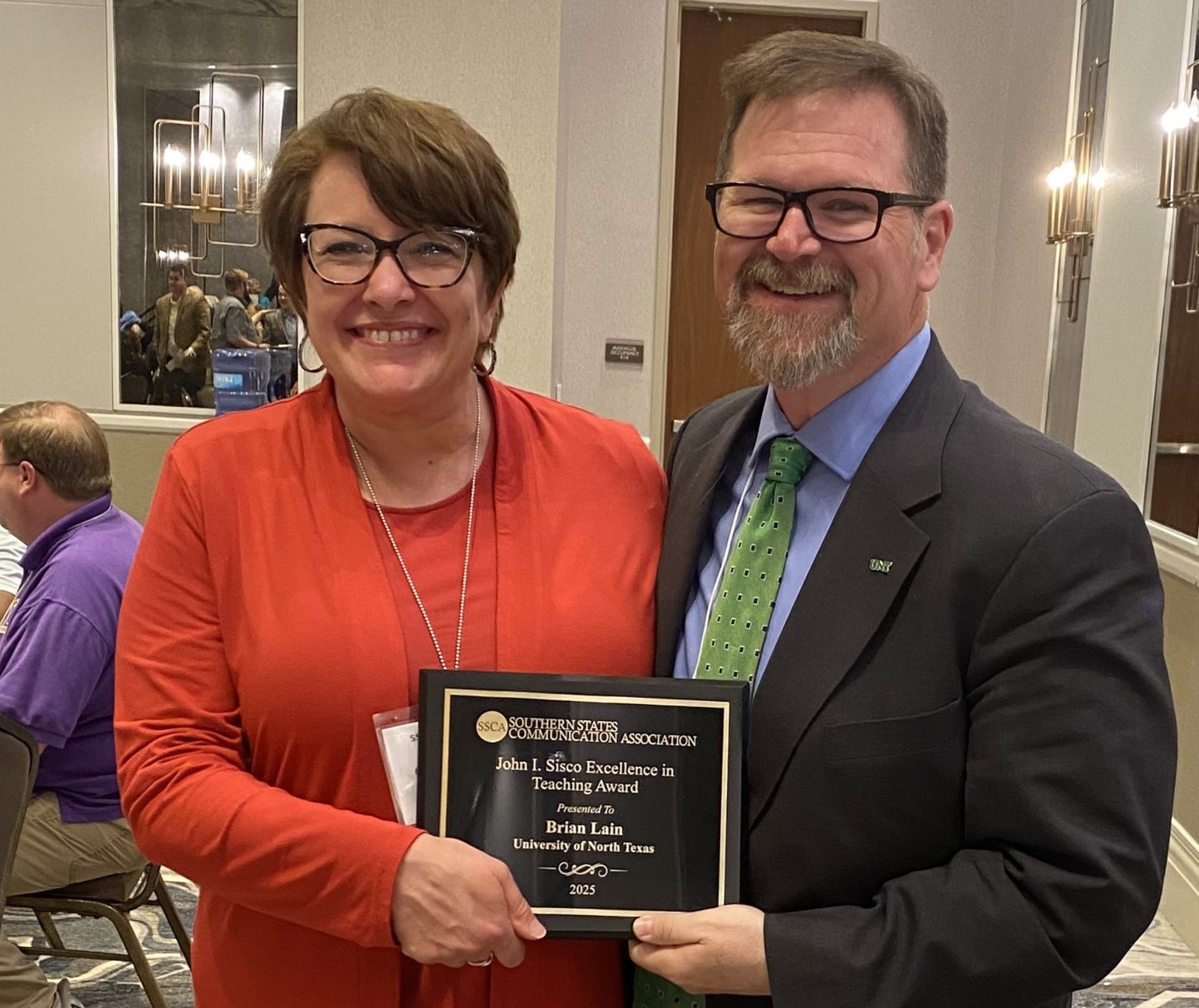 Dr. Brian Lain smiling with a woman, them both holding the John L Sisco award