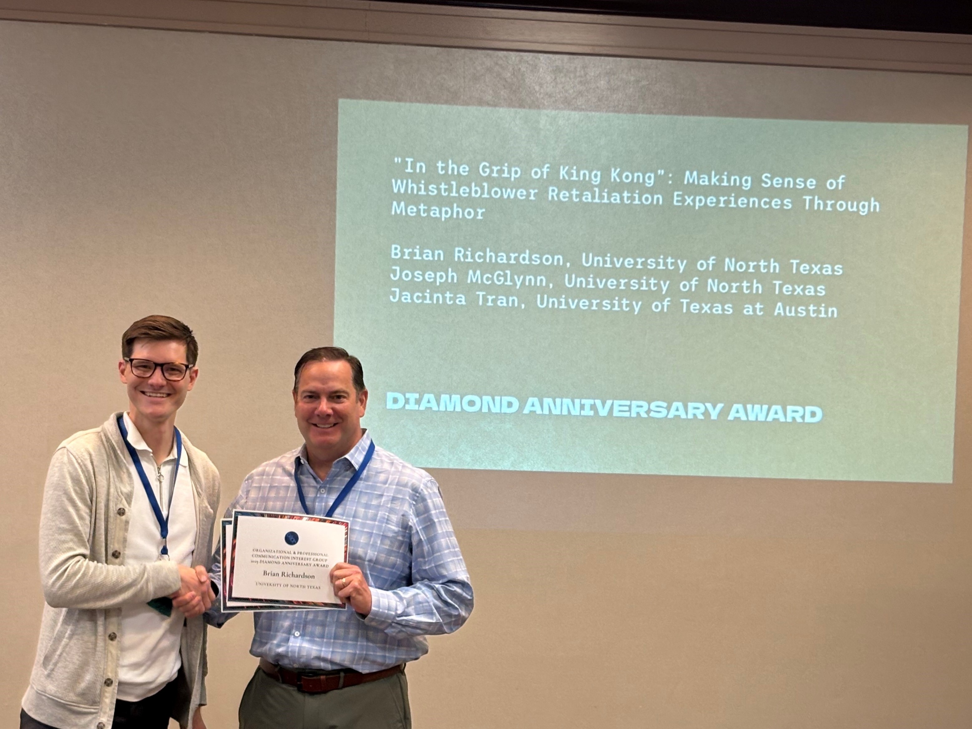 Dr. Brian Richardson holding award in front of title of paper