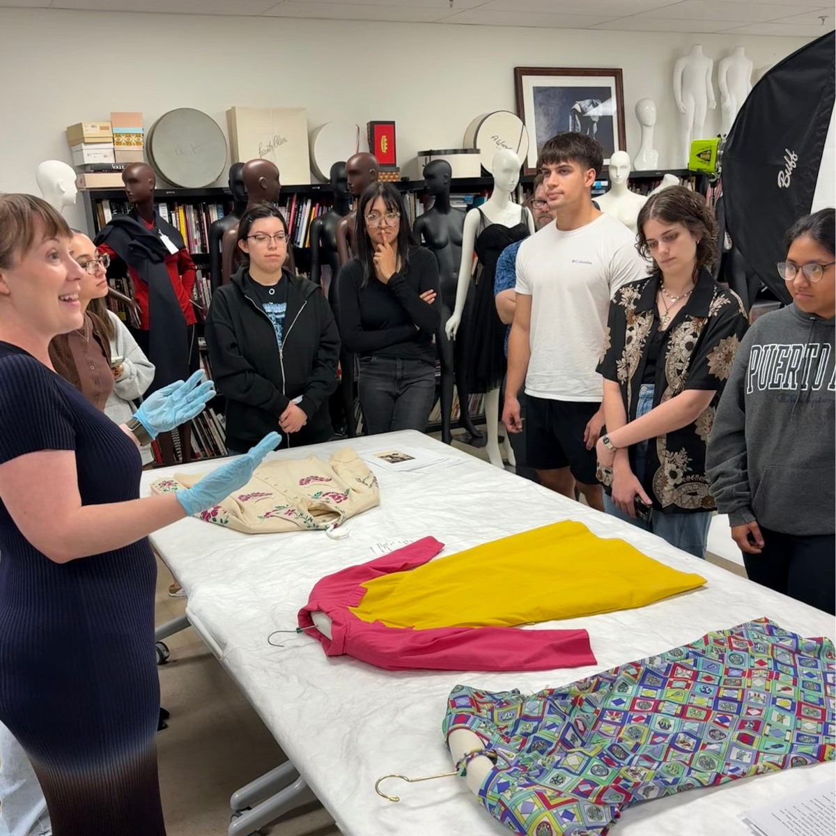 Students watch Annette Becker describe items from the fashion archive