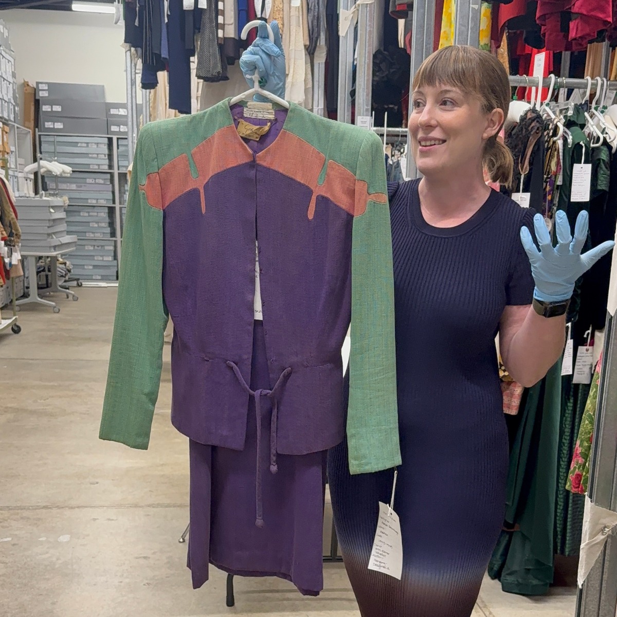 Annette Becker holding a dress from the archive on a hanger
