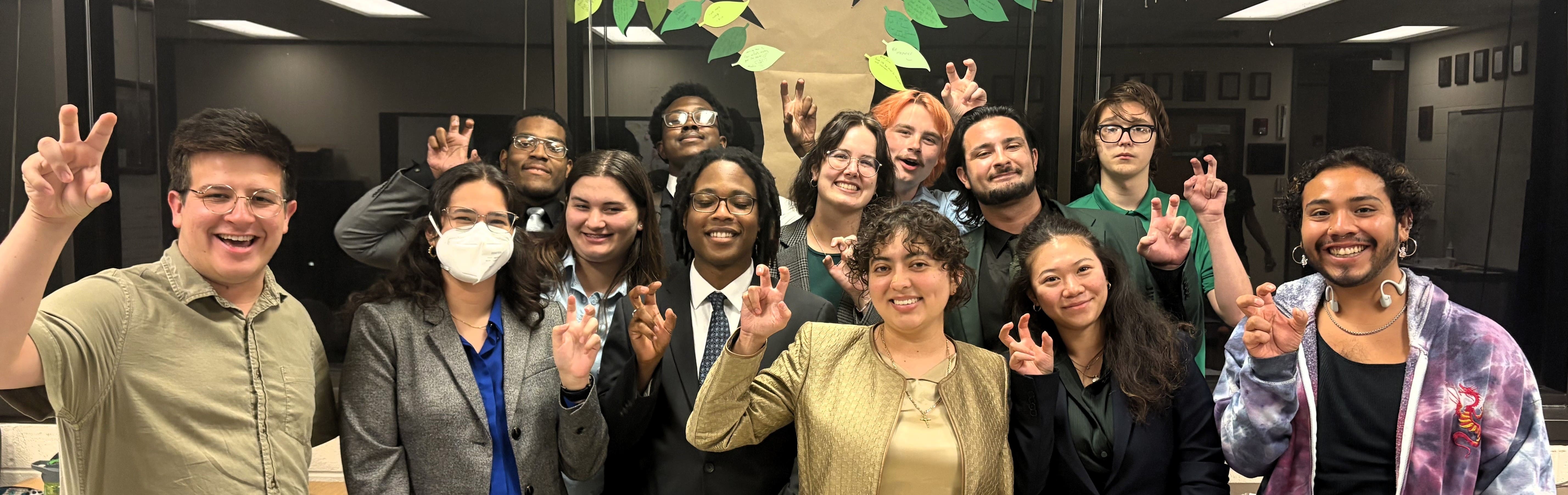 UNT Debate team members smiling for camera holding up the UNT claw with their right hands