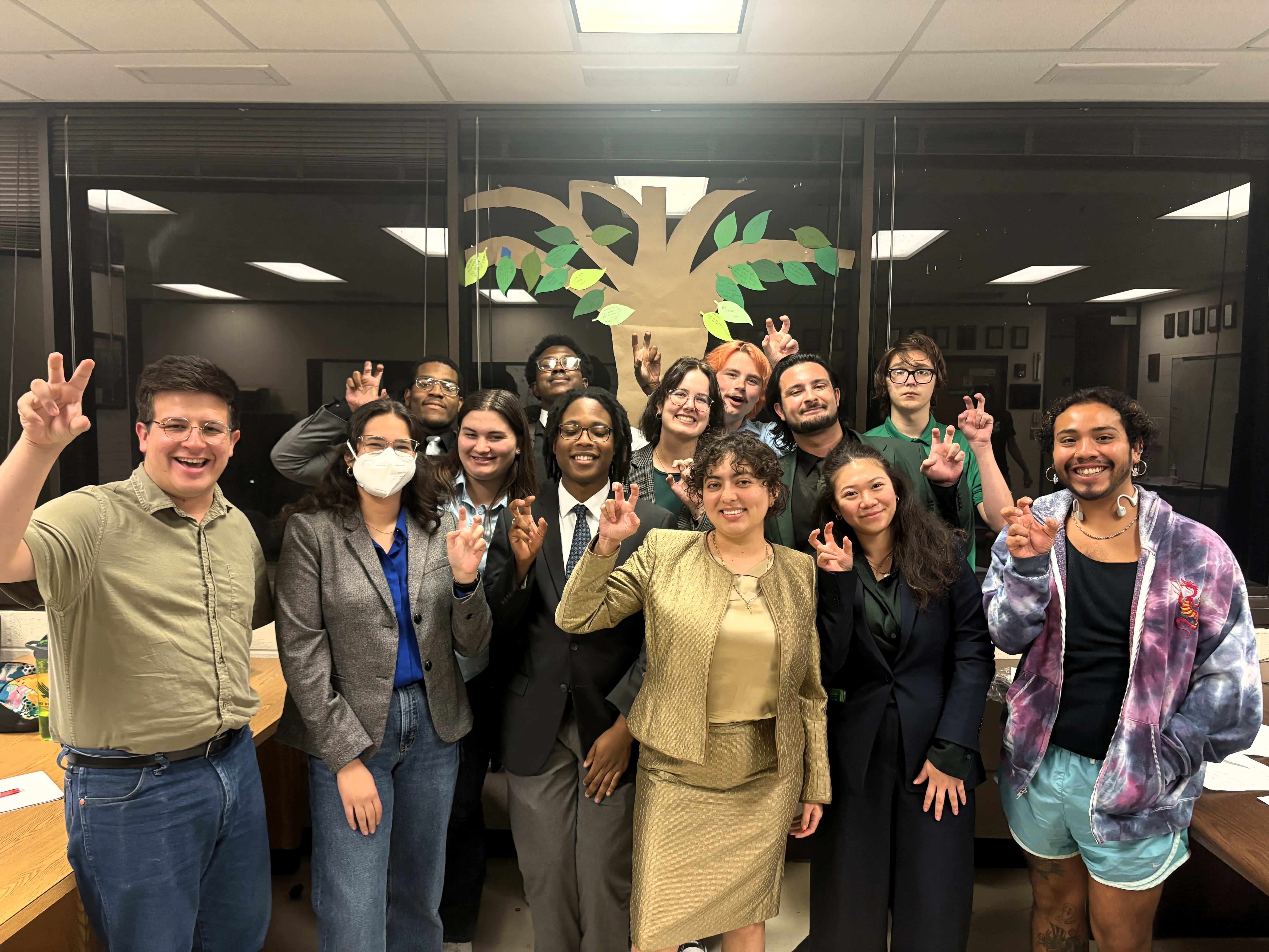 UNT Debate team members smiling for camera holding up the UNT claw with their right hands