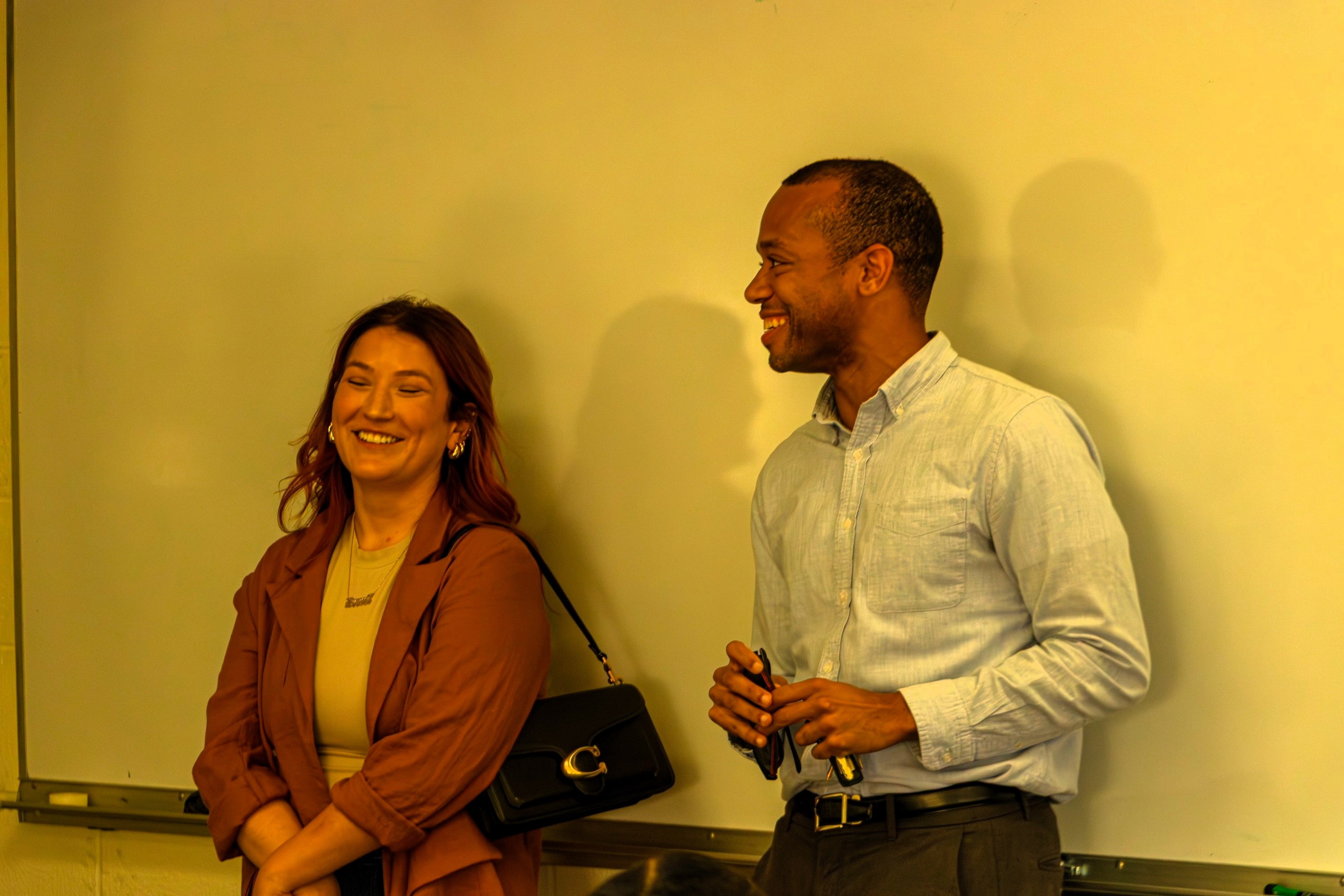Alumni speakers smiling in front of white board during presentation