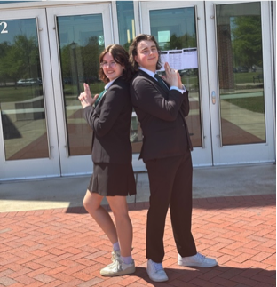 Debate contestants stand back to back with finger guns drawn