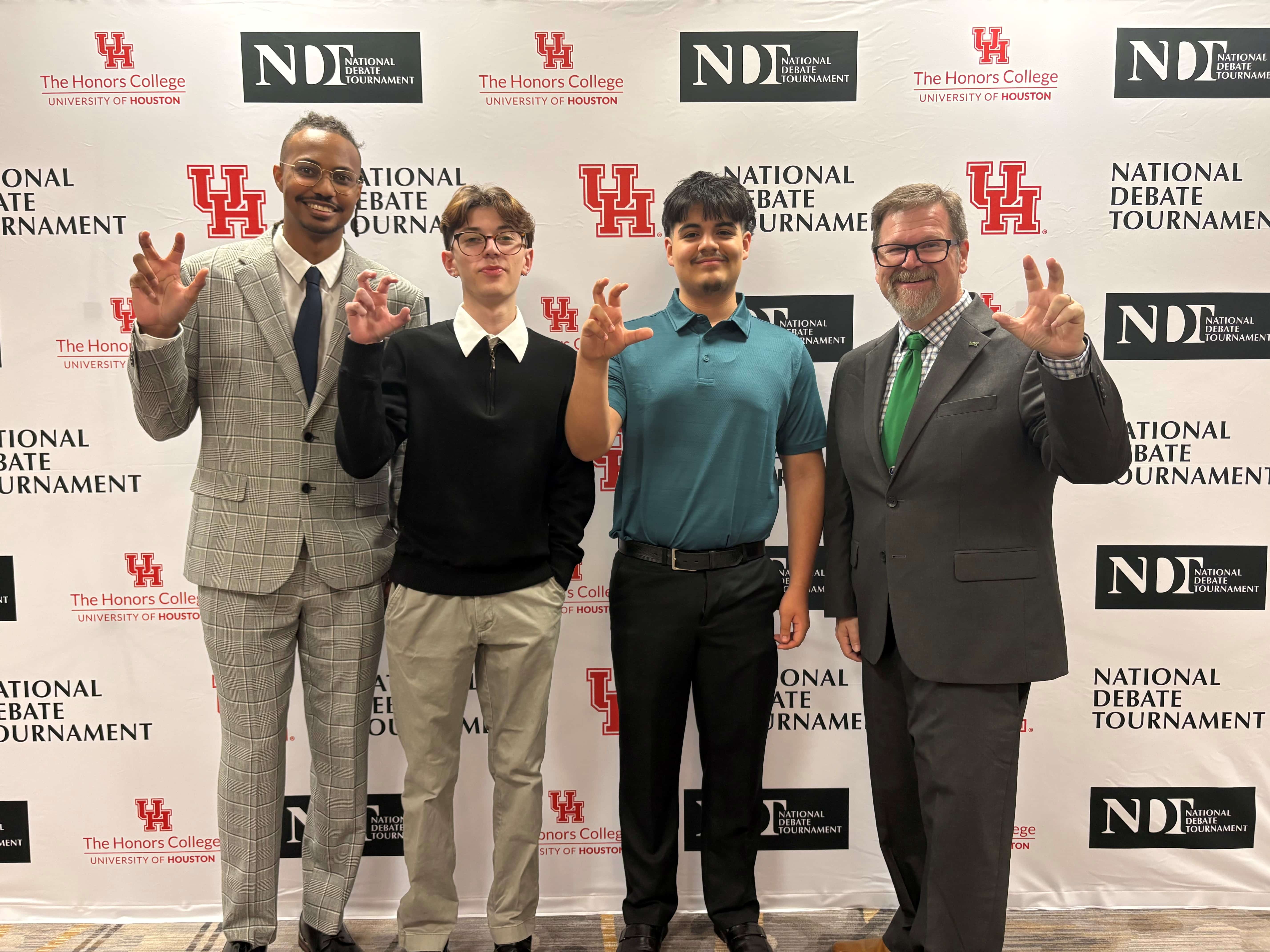 Niko Sims, Ronen Bowman, Emanuel Vargas, and Brian Lain posing in front of National Debate Tournament backdrop