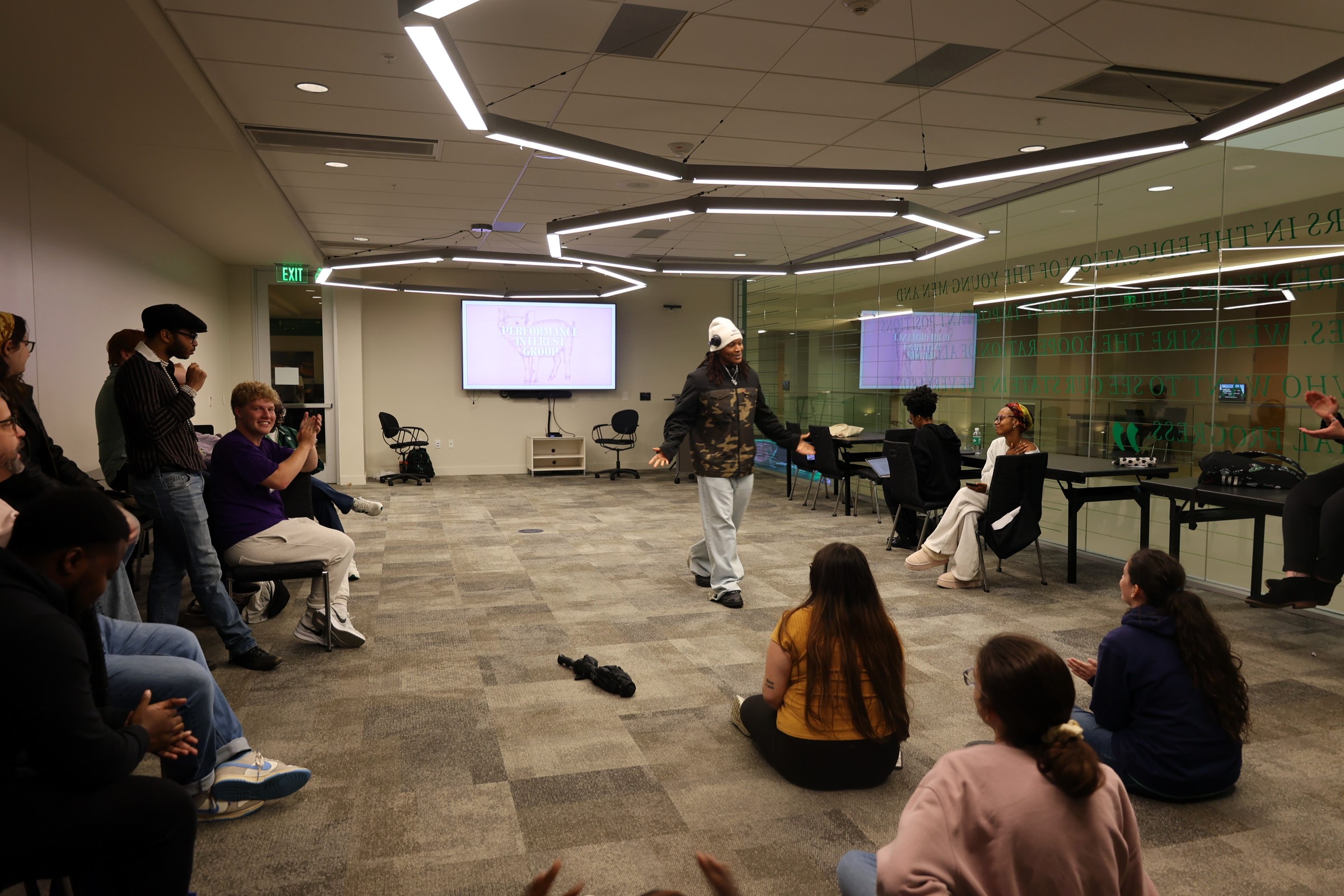 Student standing and performing as students sit around in a circle