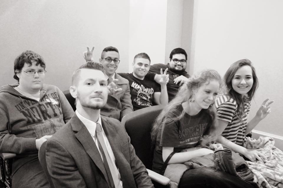 Black and white image of UNT debaters posing for picture while sitting down
