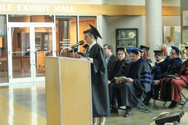 Master's graduate gives speech at commencement ceremony in cap and gown