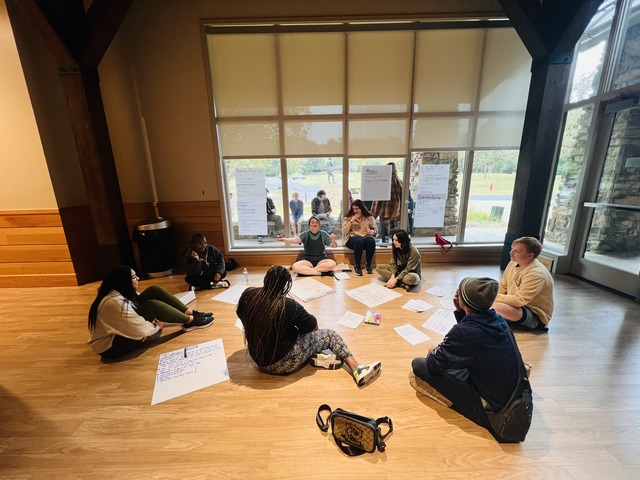 Students sit in circle on floor