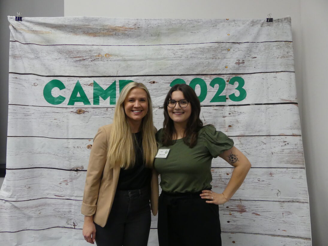 Alumni mentor and student in front of CAMP 2023 photo backdrop.