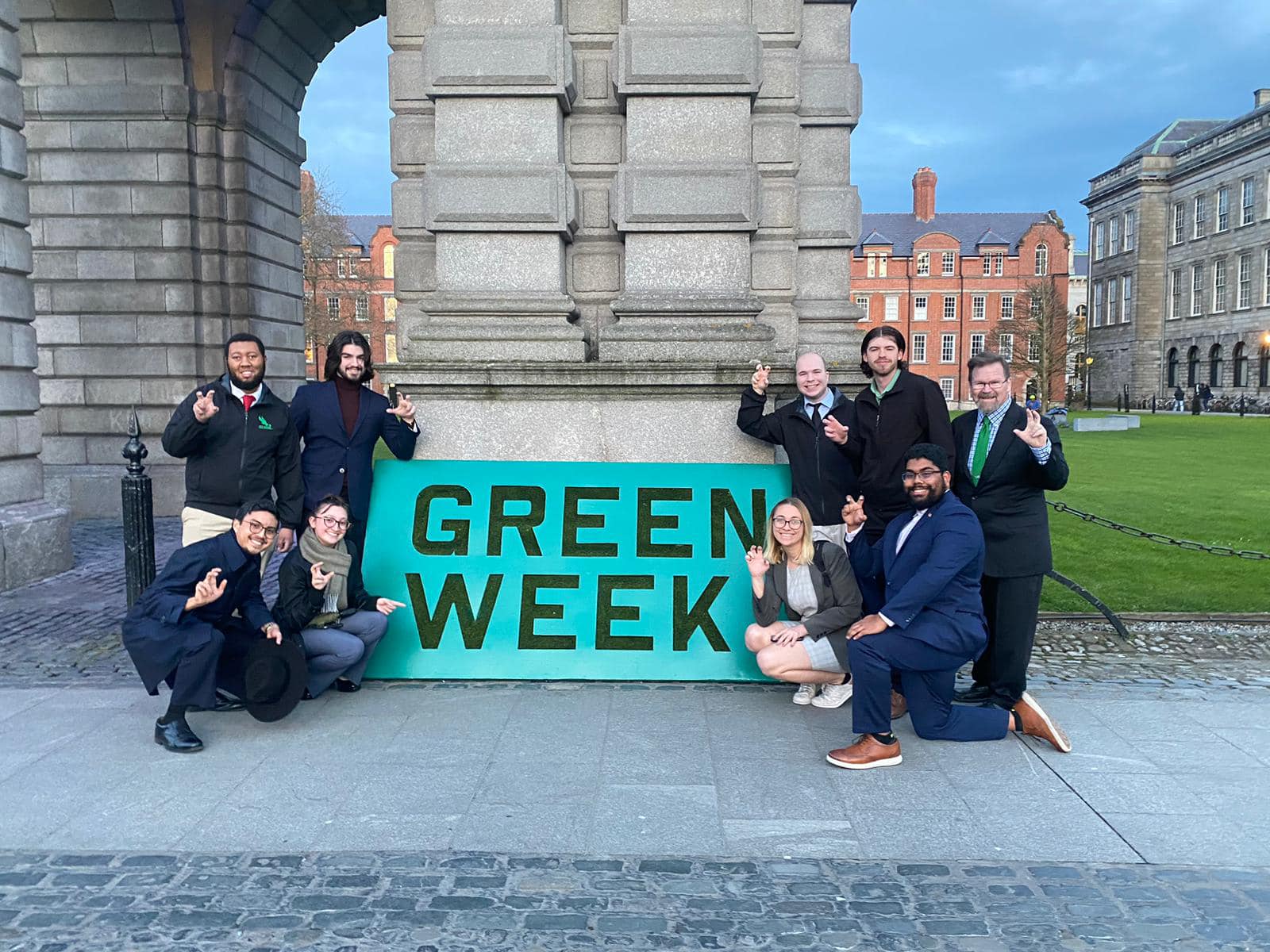 Debate team in front of Green Week poster