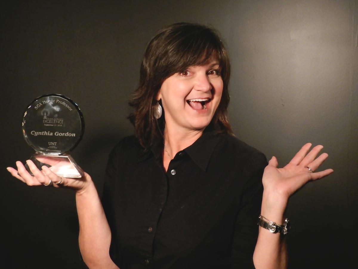 Cindy Gordon smiling and posing with a faculty award