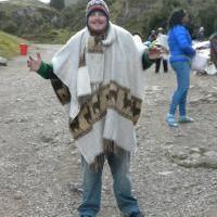 Student Lance Ragland posing in travel photo on gravel road in Peru wearing a knit poncho and beanie