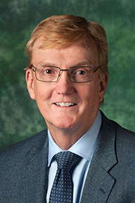 Michael C. Carroll, Ph.D. posing in front of green background