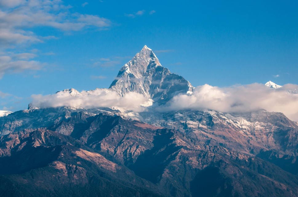 Snow-capped mountain peak rising above clouds and ridges