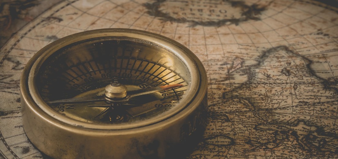 Brass compass resting on old map