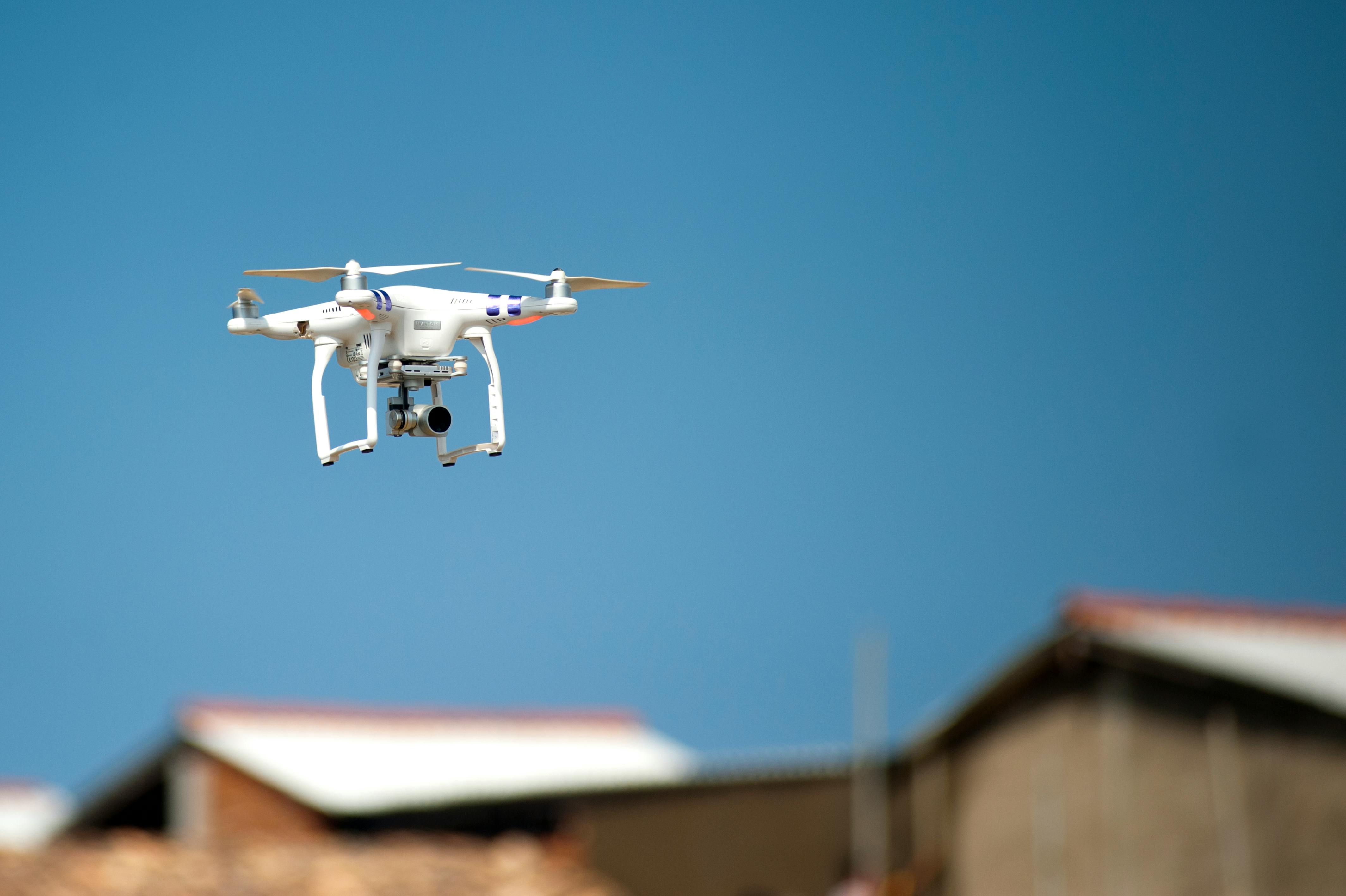 White drone flying over rooftops