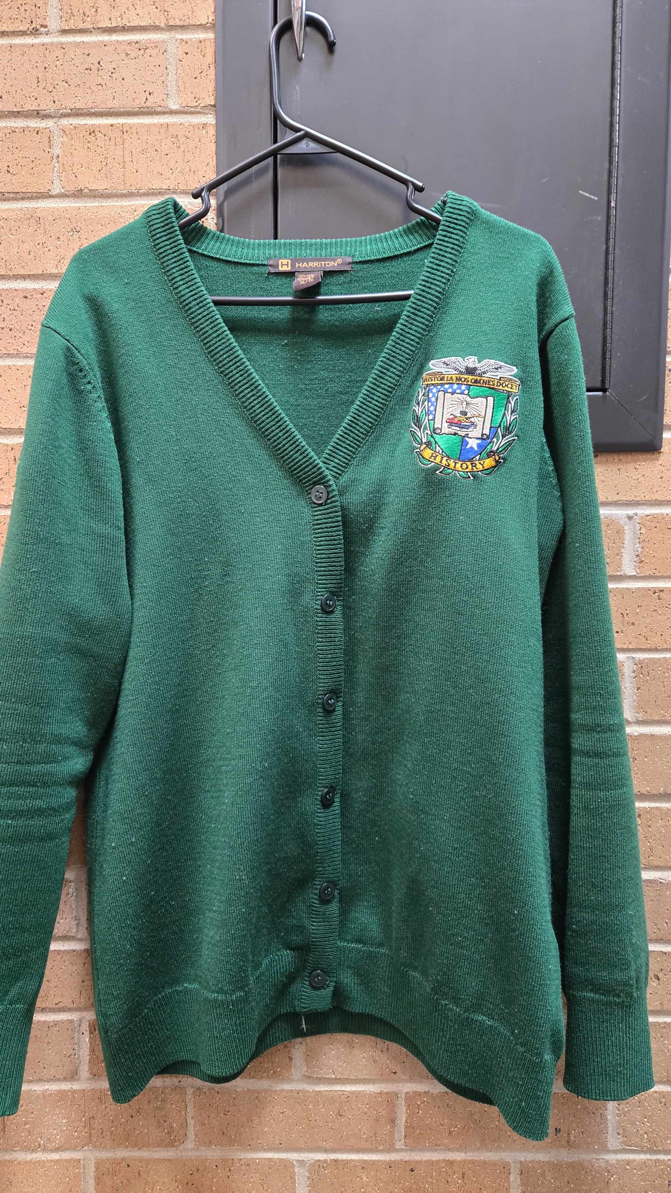 Image of Department of History Cardigan Hanging in front of red brick wall