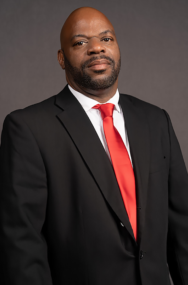 Image is of man named Erick Johnson in a suit posing for a portrait.