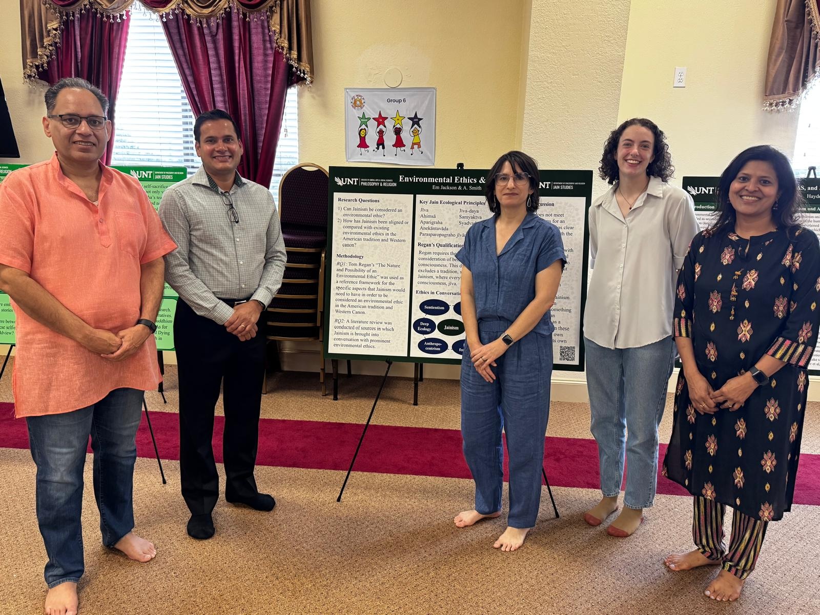 People stand in a semicircle in front of a poster.
