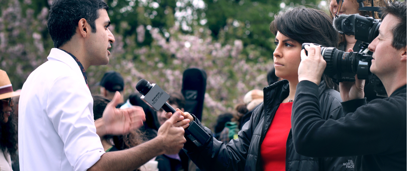 A man being interviewed by a woman with a microphone.