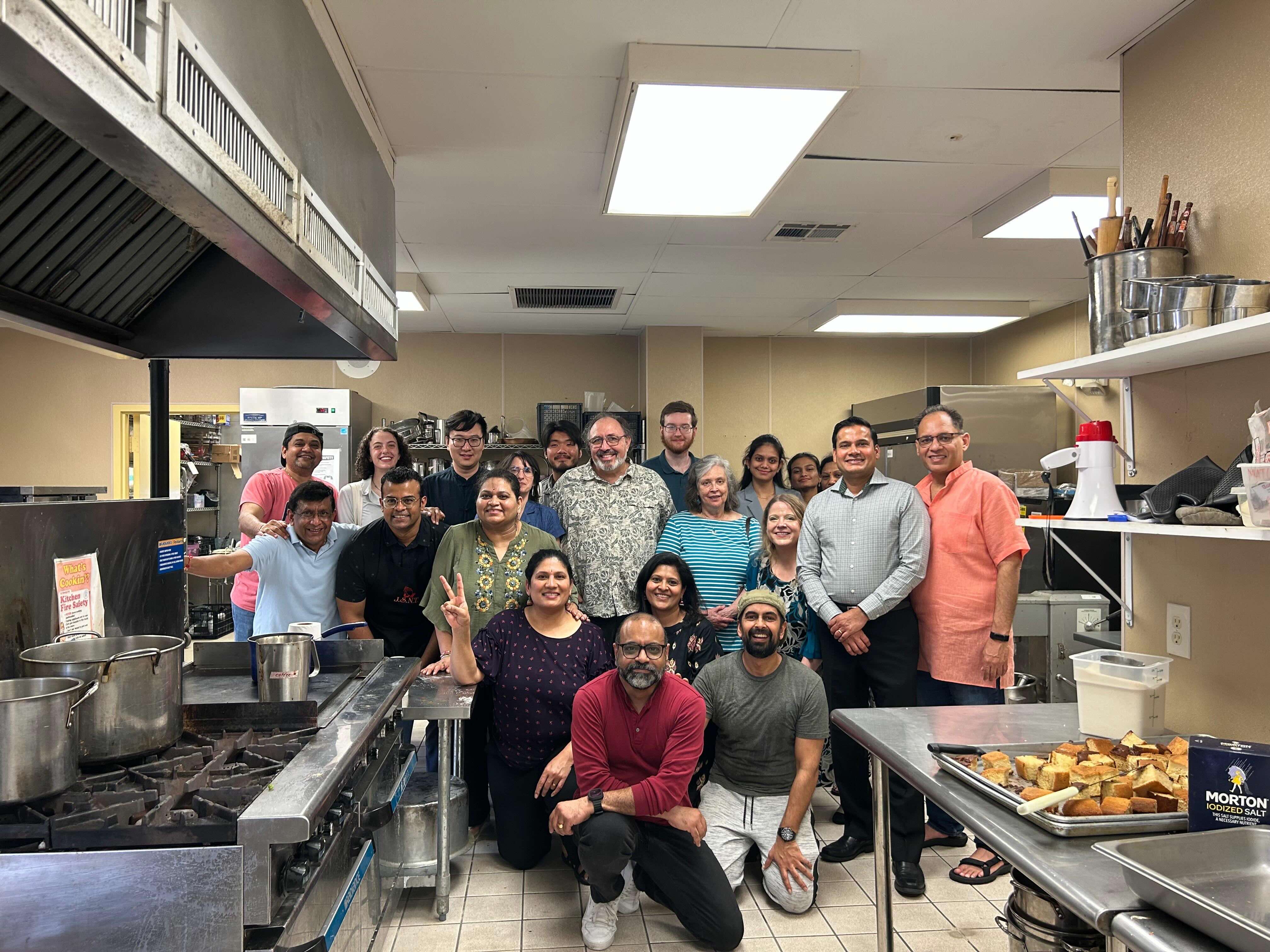 People pose in the kitchen of a cafeteria.