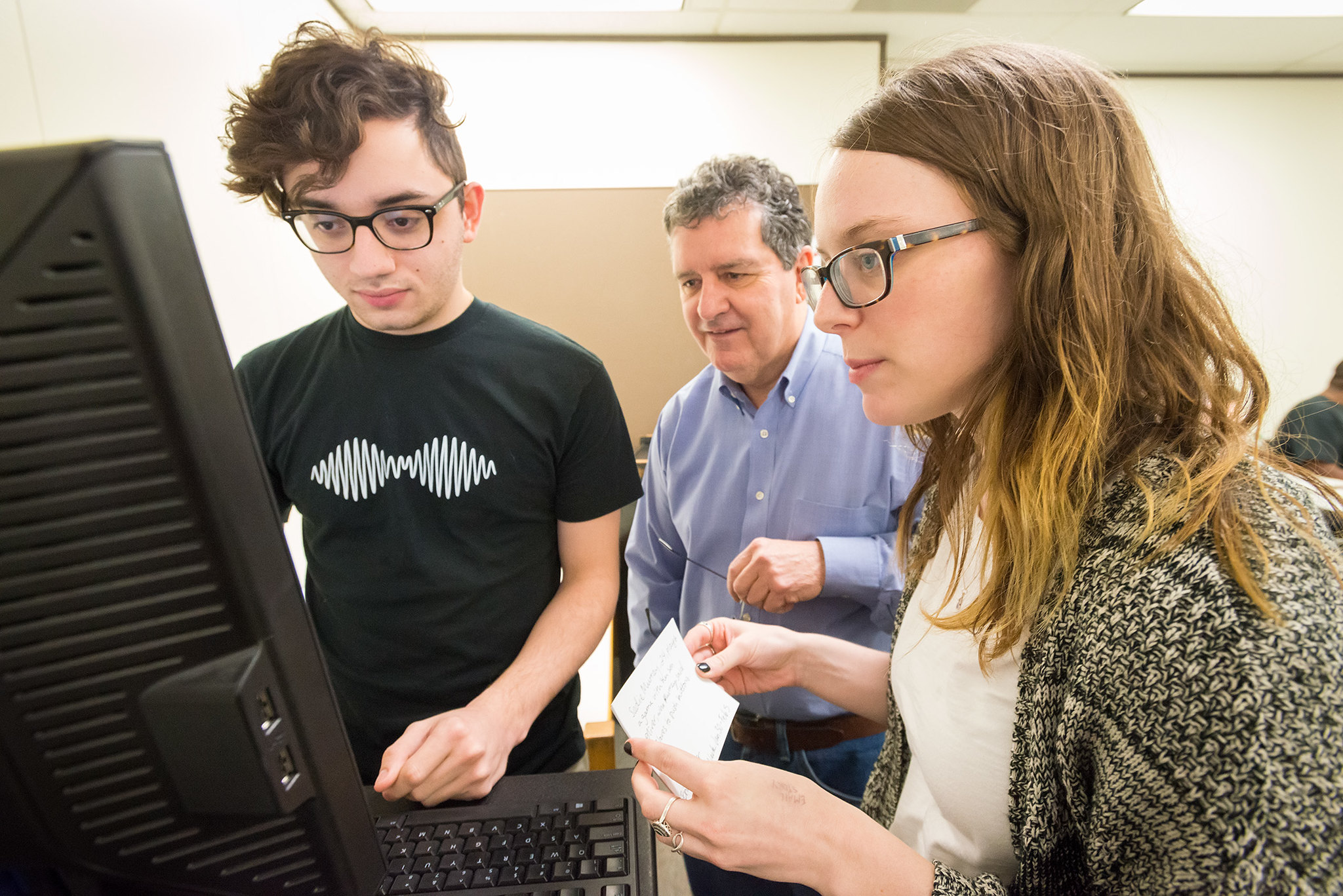 male instructor helping two students at the computer