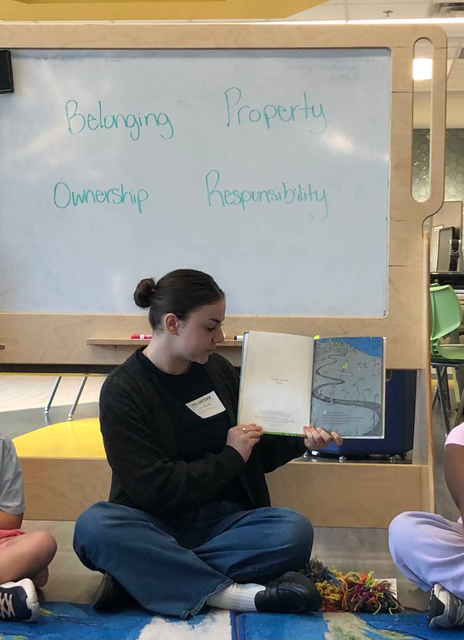 Image of Lucia reading a story book in front of a white board
