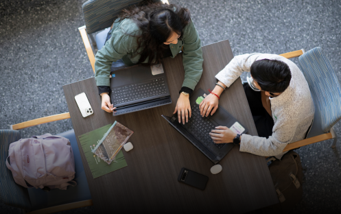 Students surrounding table with laptops